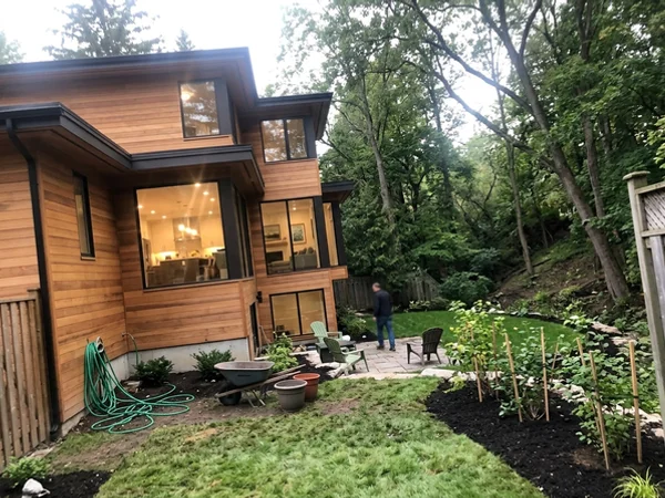 After: modern cedar and glass custom home on the same Aldershot lot at dusk