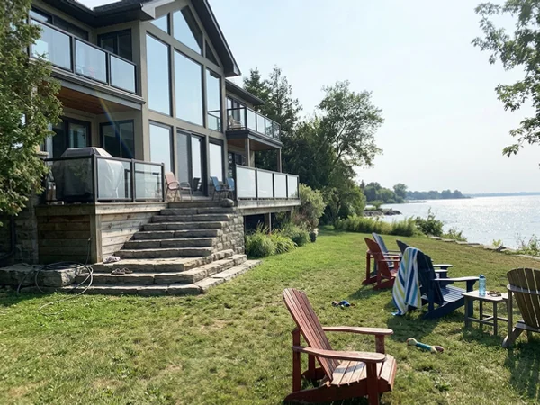 After: raised luxury lakefront custom home facing Lake Ontario at dusk