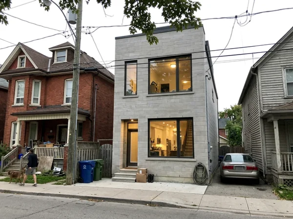 After: slim modern limestone custom home on a narrow downtown lot at dusk